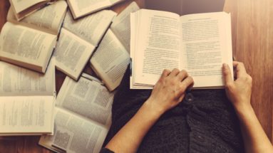 An editor reading and editing with books on the floor