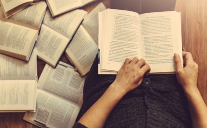 An editor reading and editing with books on the floor