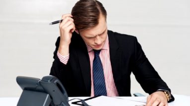 Stressed business man writing at his desk