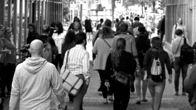 black and white photo of a city street with many different people walking on footpath