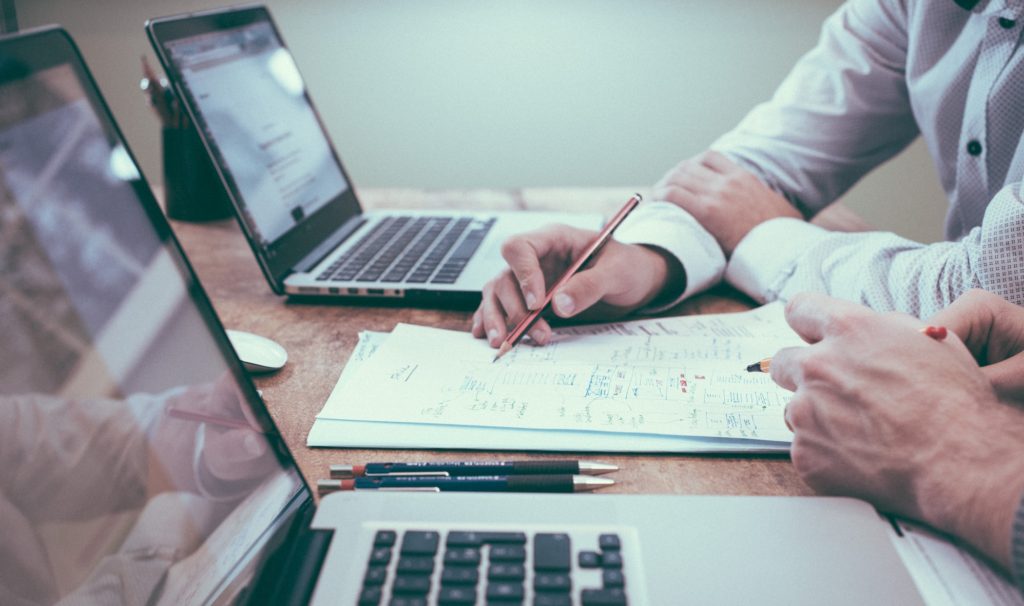 2 business people with 2 laptops reviewing some papers